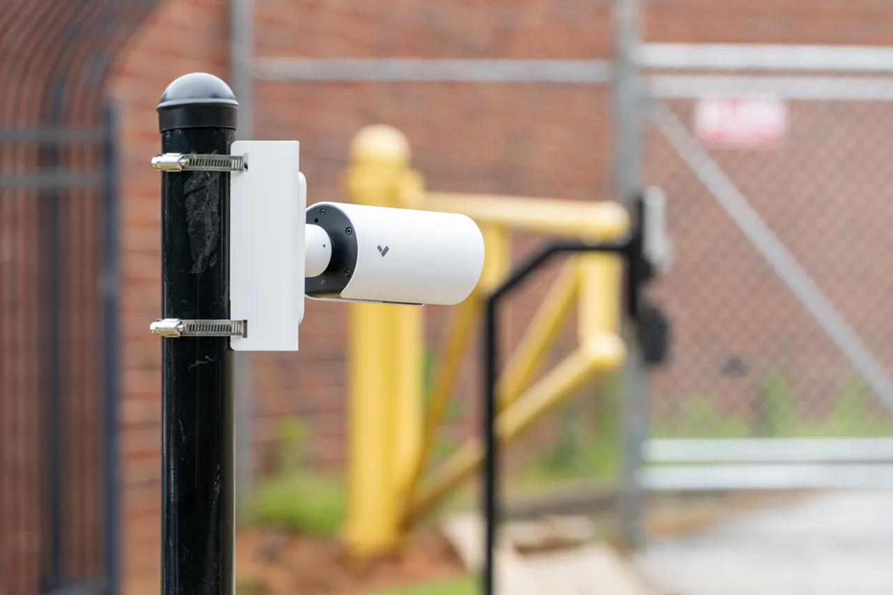 Verkada bullet camera mounted on a black pole at a building exterior perimeter.