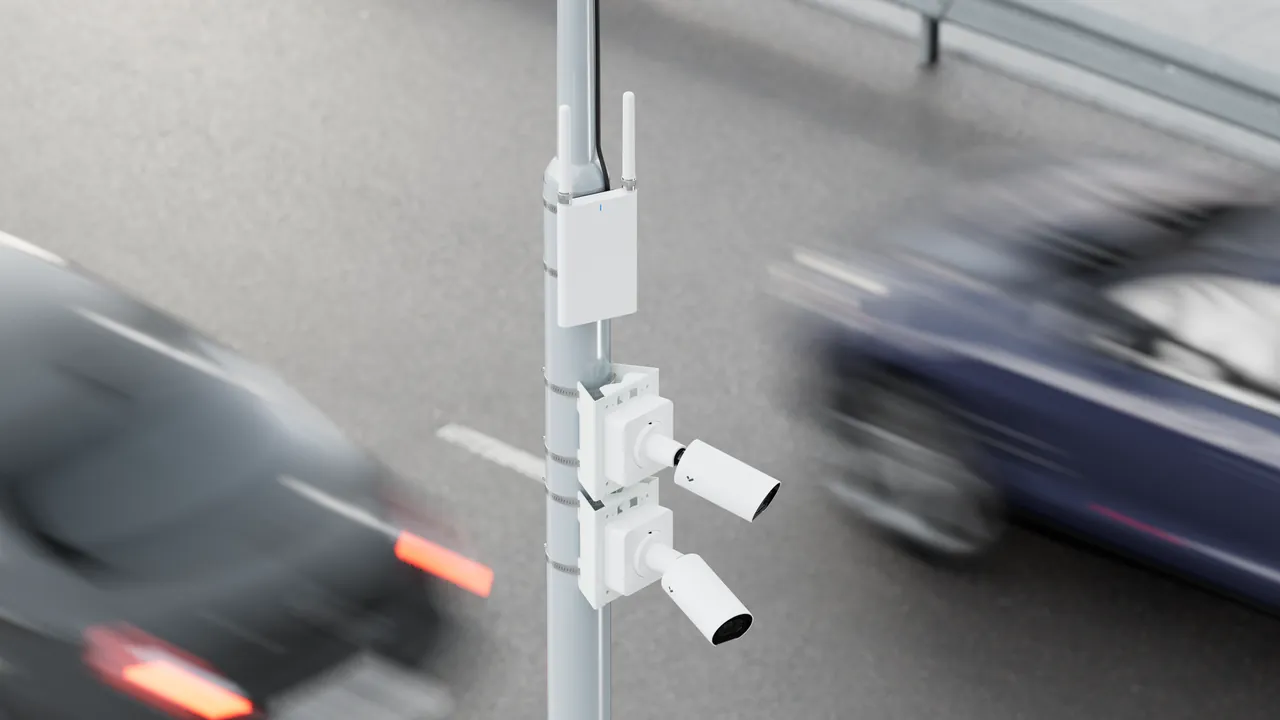 Two Verkada bullet cameras and a wireless router mounted on a roadside pole.