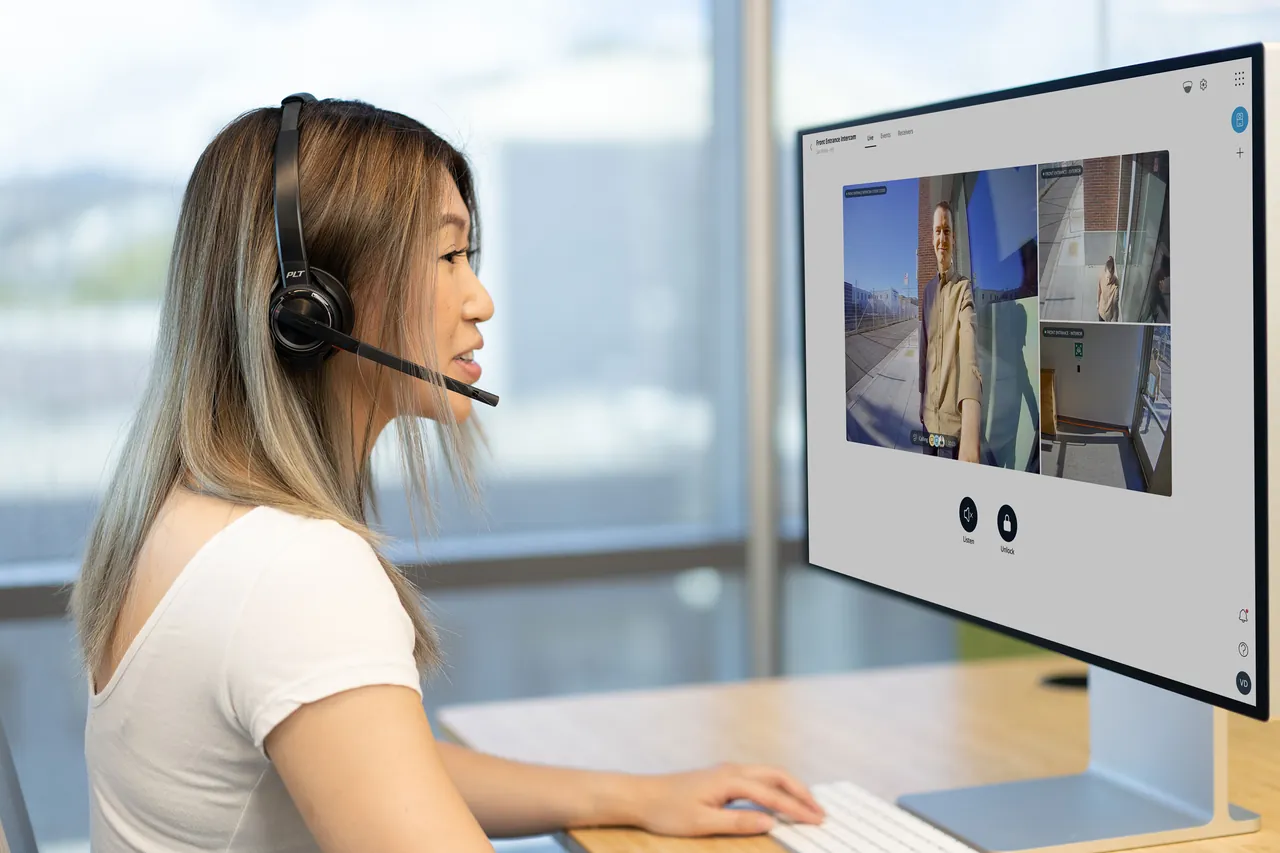 A receptionist wearing a headset answers a Verkada intercom call at her desk.