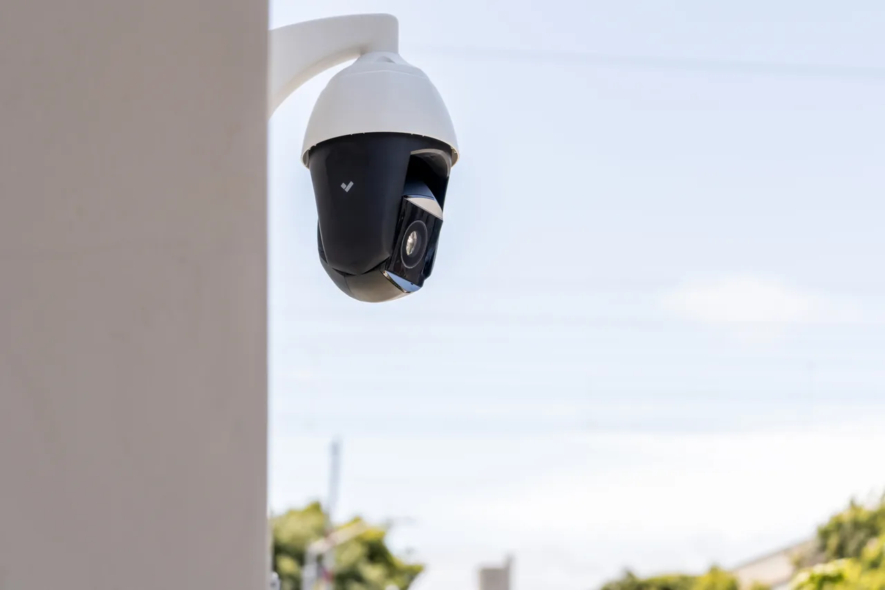 Wall-mounted PTZ dome camera on an outdoor pillar, managed by ip camera software to enable remote pan-tilt-zoom control.