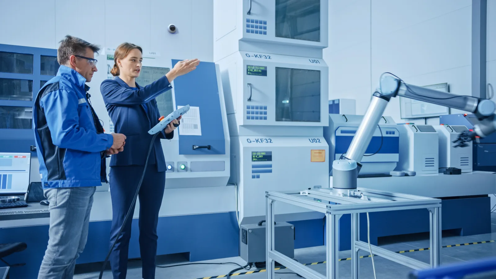 A security expert and a plant operations lead reviewing a camera-and-door plan on a manufacturing floor