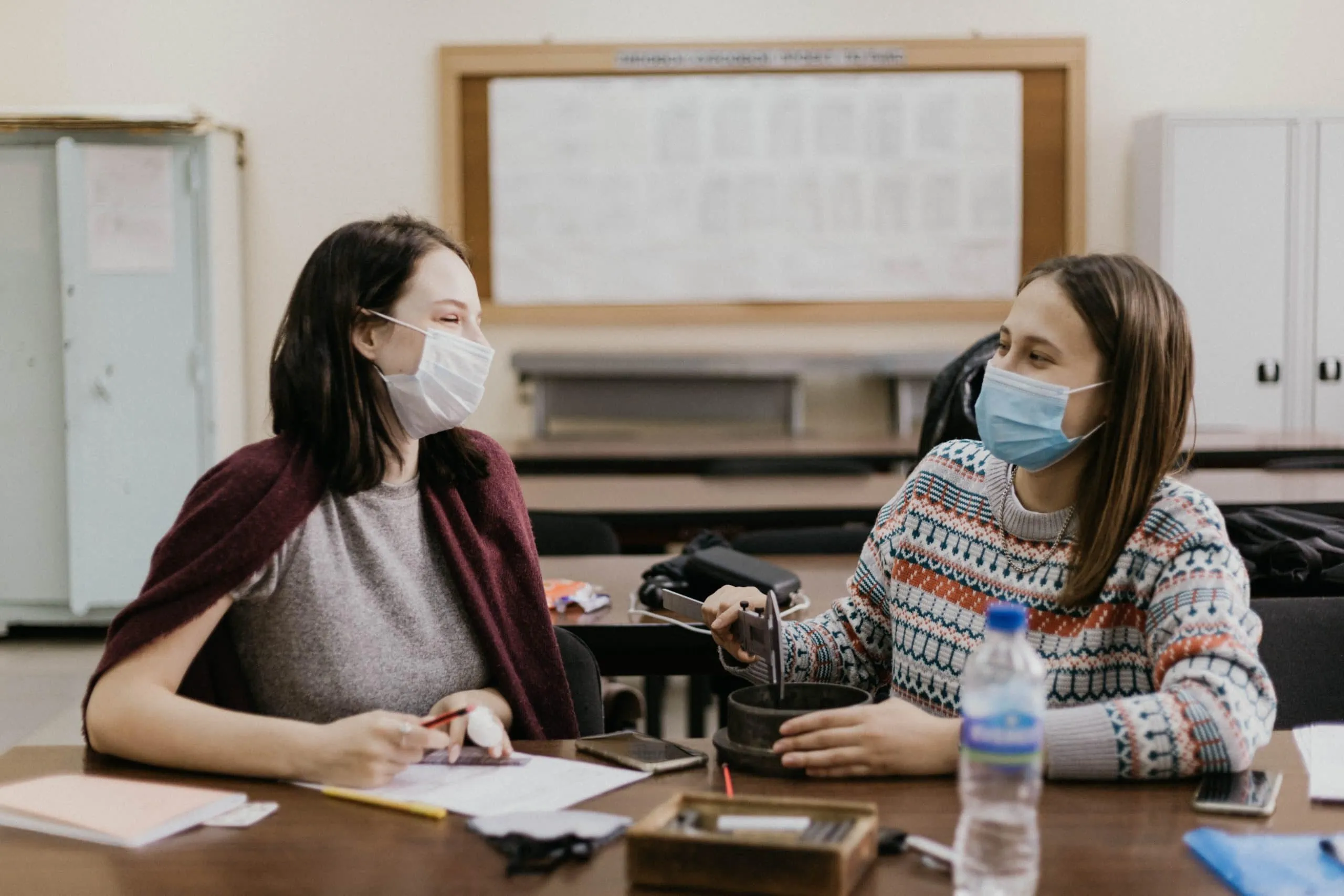 Two students wearing masks in a school with security measures