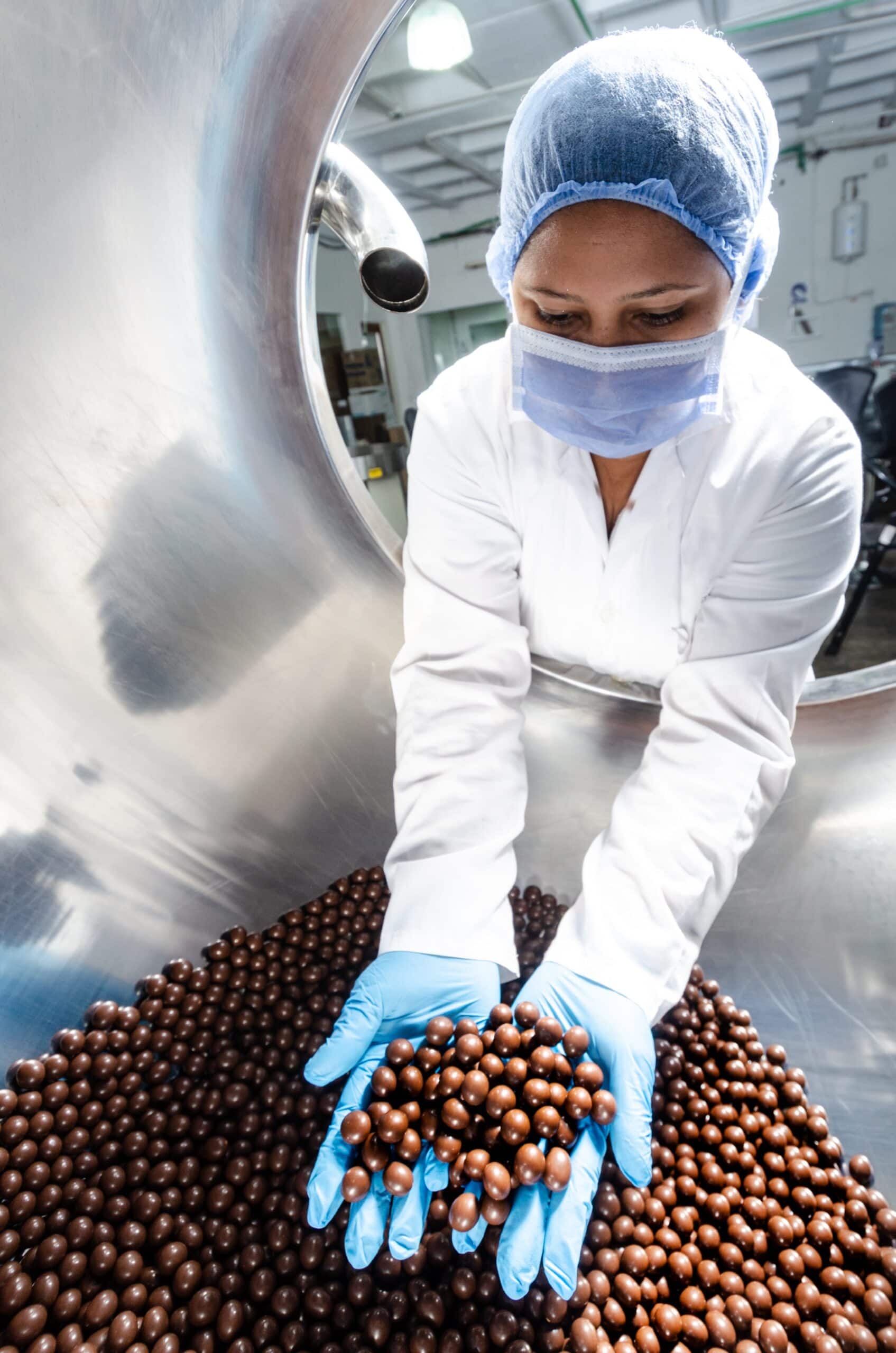 Woman wearing the appropriate protections in food facility looking at beans after reviewing alert from the Samsara EM21 environmental monitor