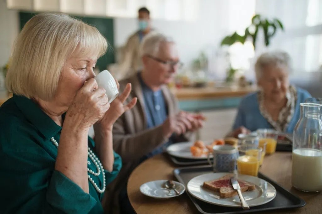 Woman drinking tea while wondering, “are cameras allowed in assisted living facilities?”