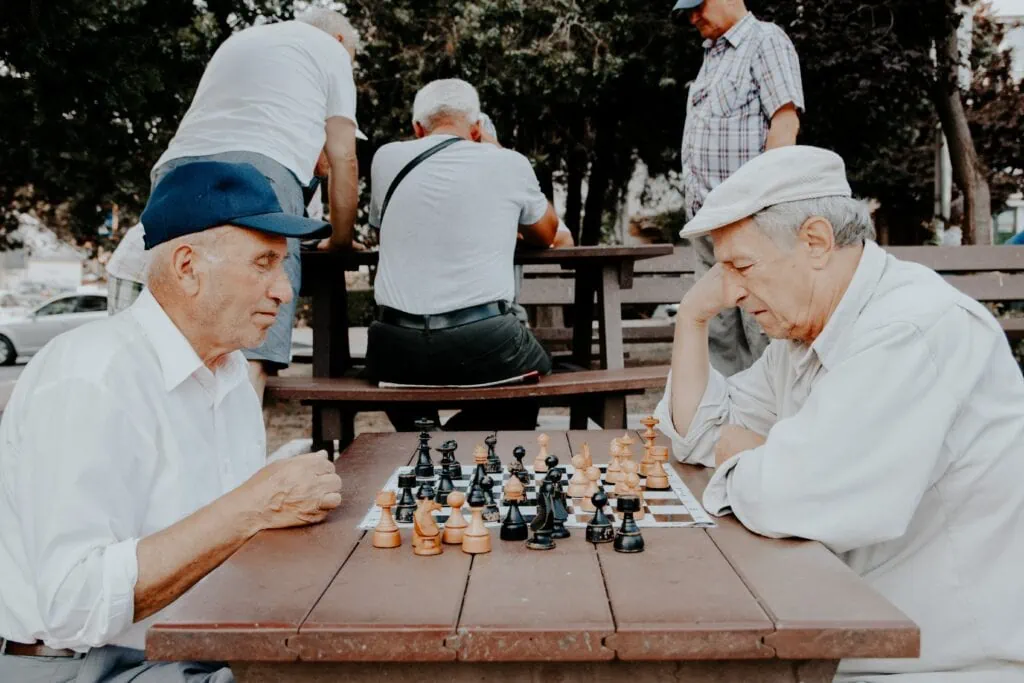 Elders playing a game of chess wondering, “Are cameras allowed in assisted living facilites”