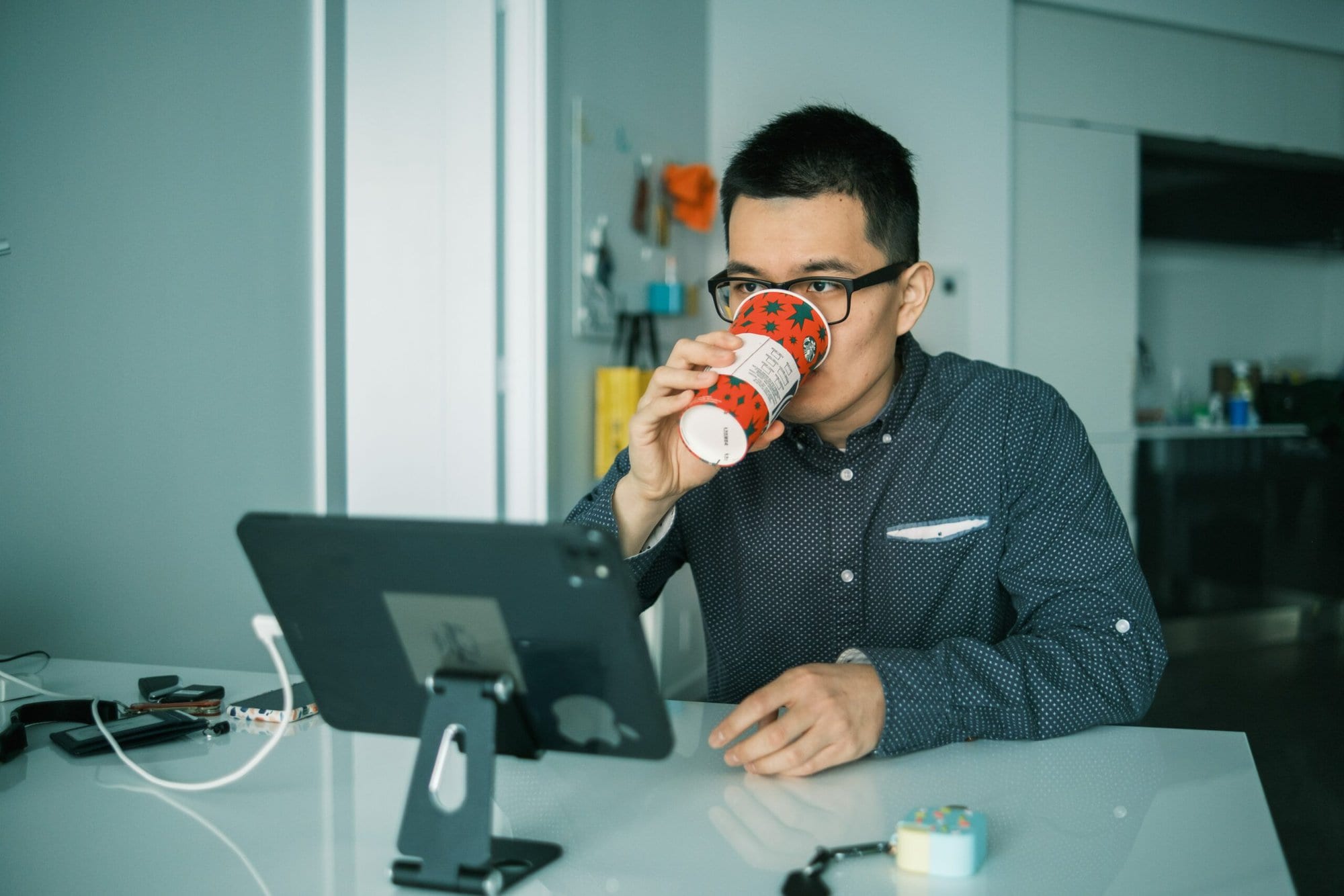A man sips coffee while engrossed in his computer, researching the NVR meaning.