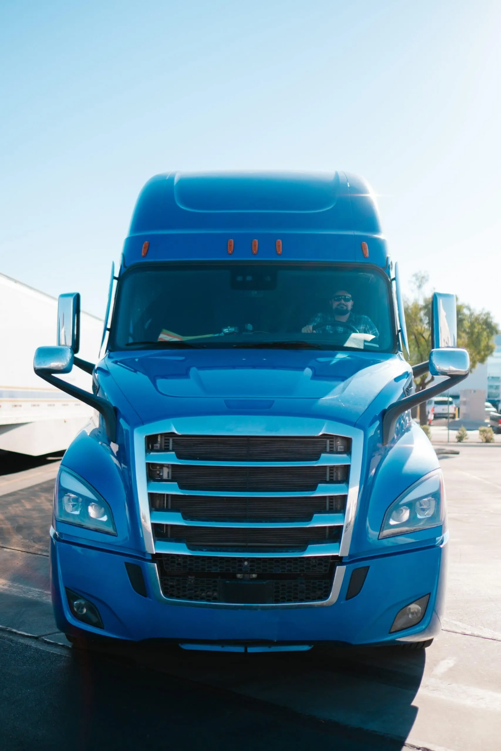Blue semi-truck, captured from the front, with a trucker inside being coached by GPS tracker with camera