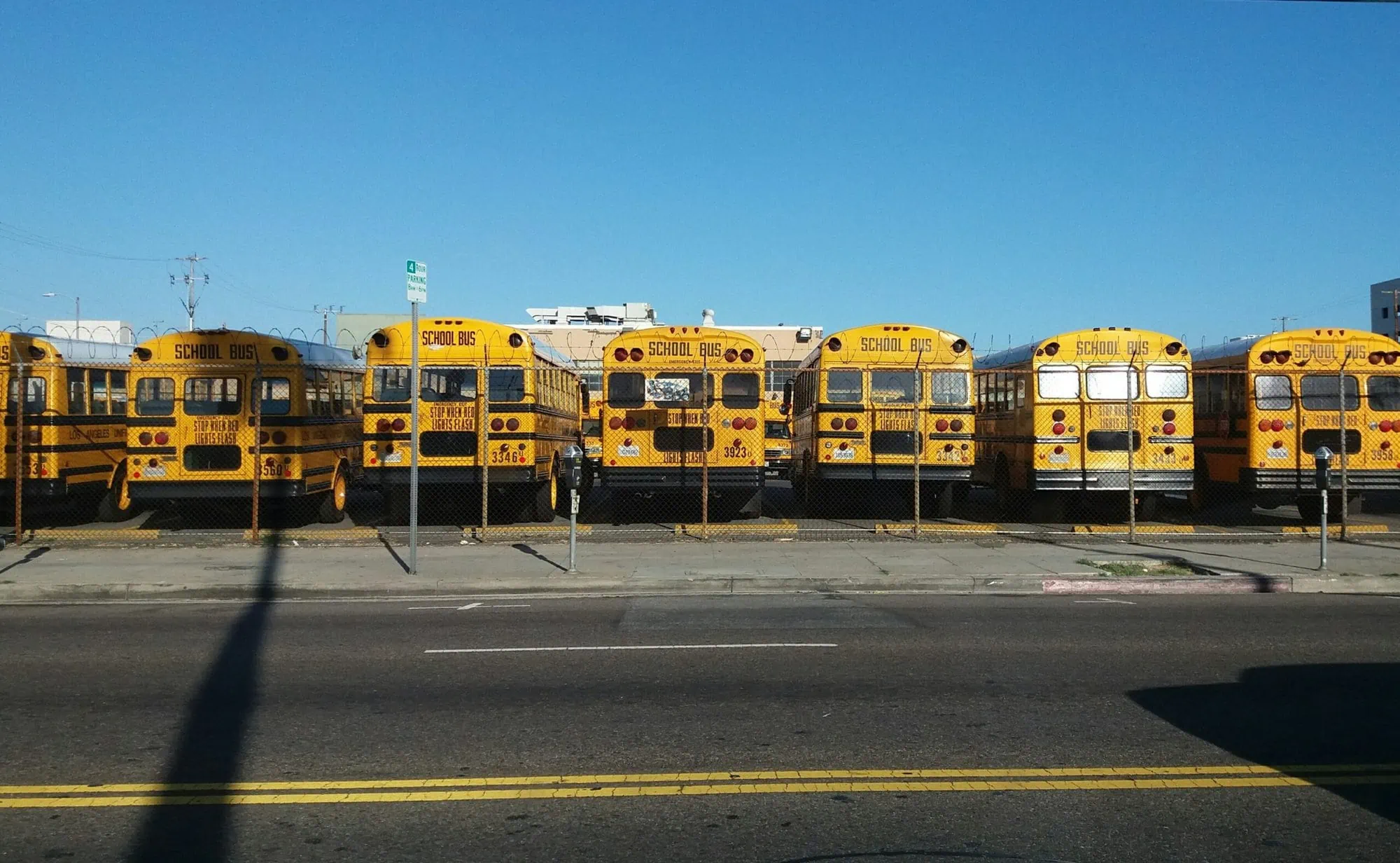 Row of district buses in parking lot, all secured with school bus camera systems