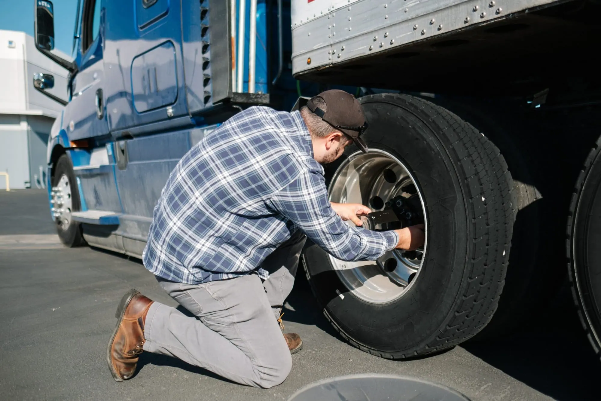 Semi truck driver fixing his tire while wondering that there is not doubt dash cameras are worth it since the system alerted him of truck issue