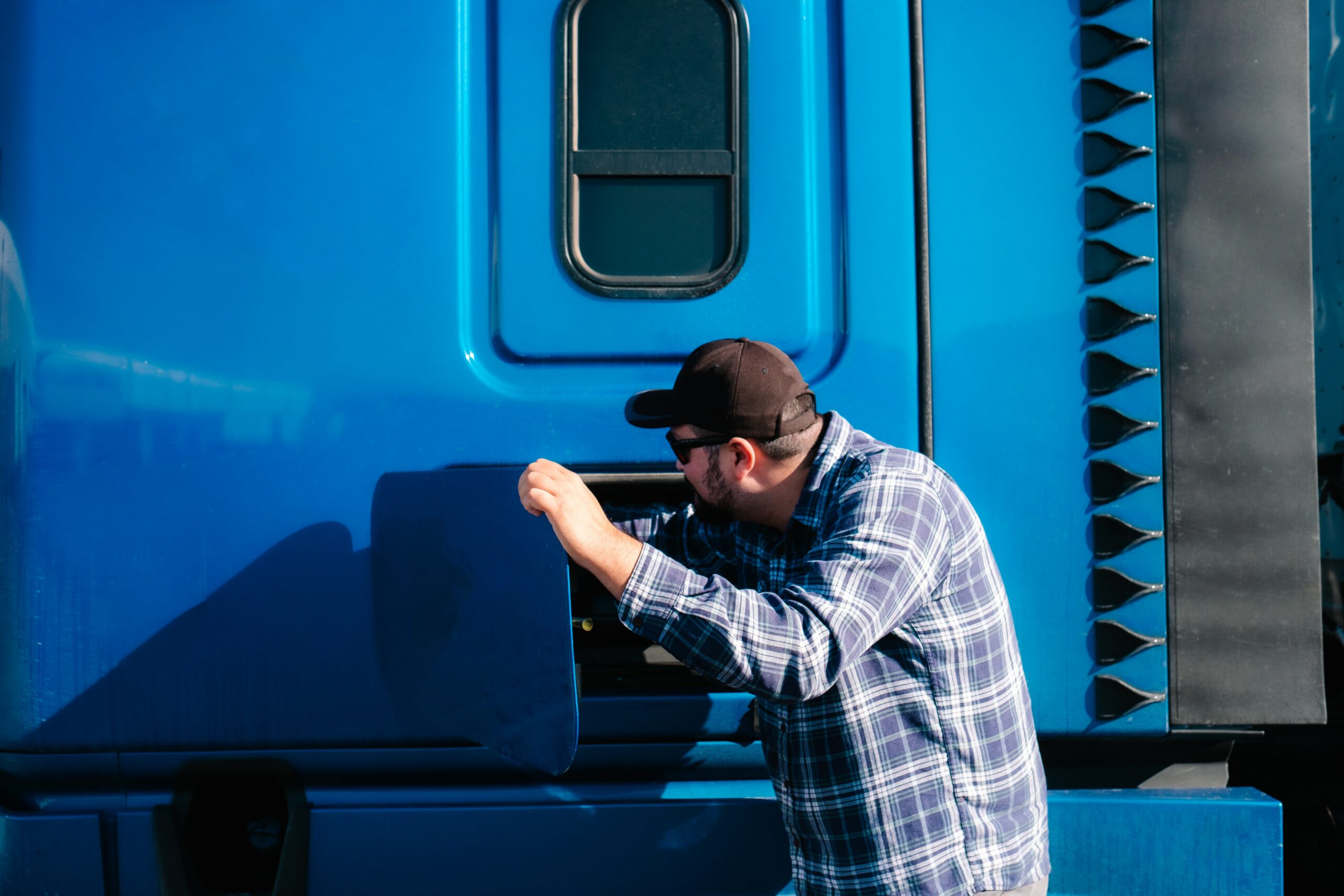 A man opening the door of a blue semi truck equipped with GPS tracker dash cam.